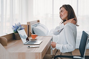 Picture of a woman sitting at a desk with neck and back pain