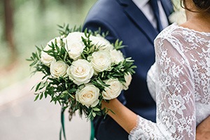 picture of a married couple on their wedding day holding a bouquet of white roses
