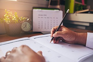 Picture of a person writing on a desk calendar
