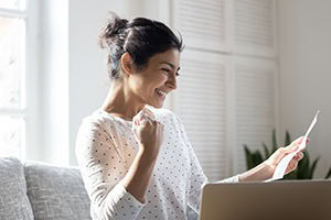 Picture of a woman sitting on couch looking happy reading document