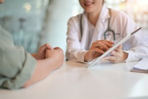 Picture of a doctor speaking to a patient, reviewing medical records