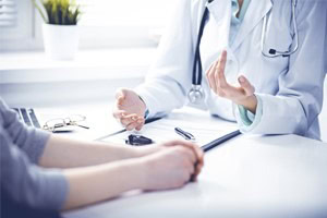 Picture of a patient sitting at desk speaking with a doctor in a lab coat