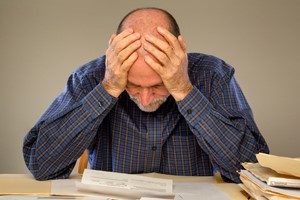 man looking upset and overwhelmed reviewing documents