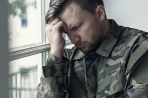 Soldier with PTSD sitting and looking upset.