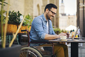 Man-sitting-in-wheelchair-at-cafe-on-laptop