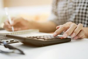 picture of a person at sitting at desk writing notes and using a calculator