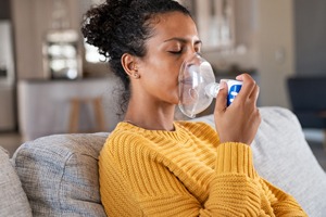 Picture of a woman sitting on couch using an oxygen treatment