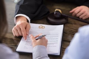 Picture of a couple sitting with attorney signing divorce papers