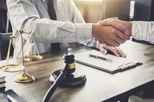 Picture of a lawyer and a client sitting and talking at a desk, shaking hands
