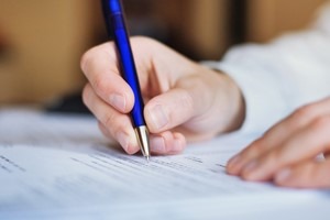 person filling out a form with a pen